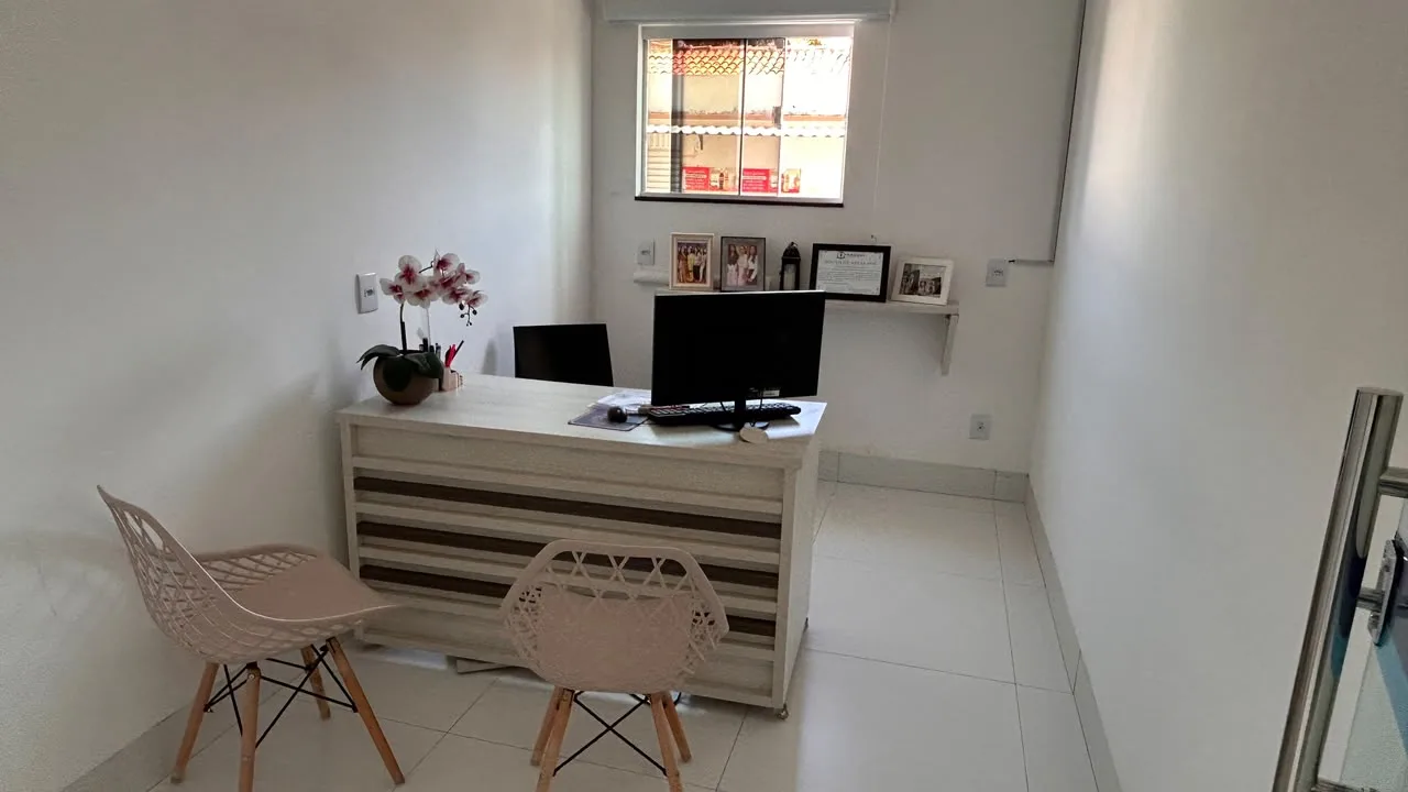Sala da secretaria com mesa de atendimento, computador e diplomas na parede