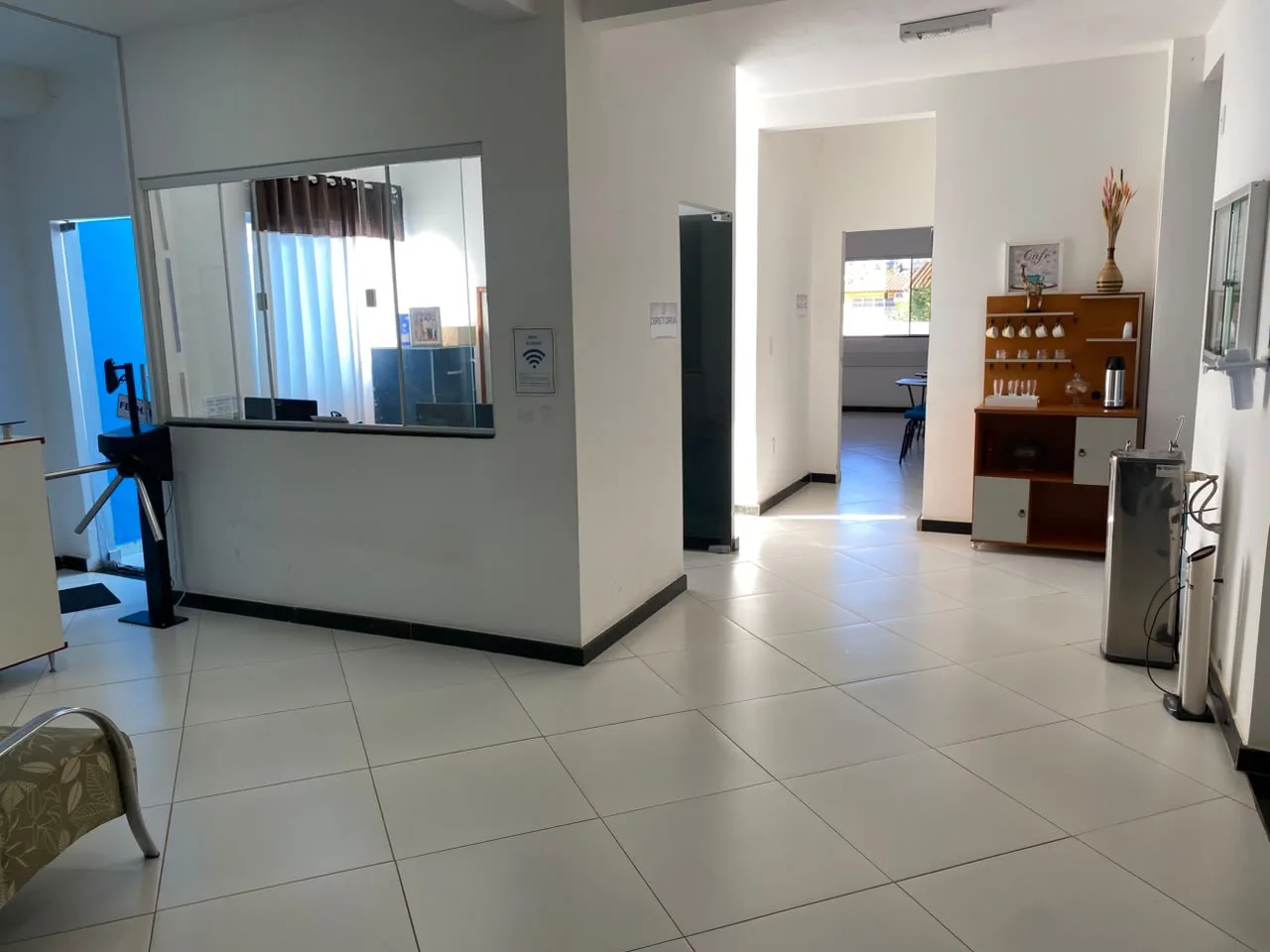 Guiche da secretaria no hall de entrada, com catraca de acesso e bebedouro